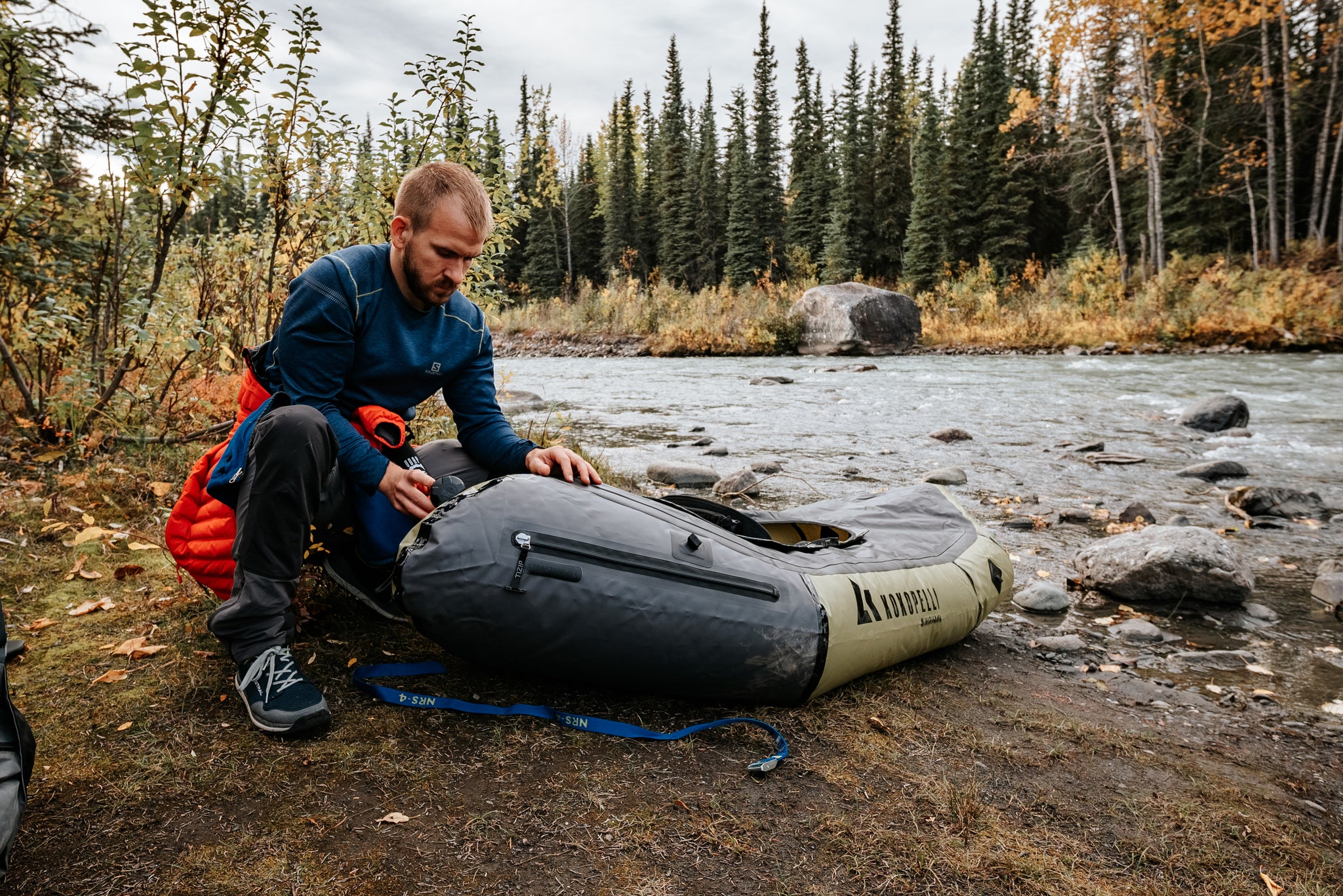 Nick Coulter blowing up his Nirvana Spraydeck Packraft with a Feather Pump next to a river