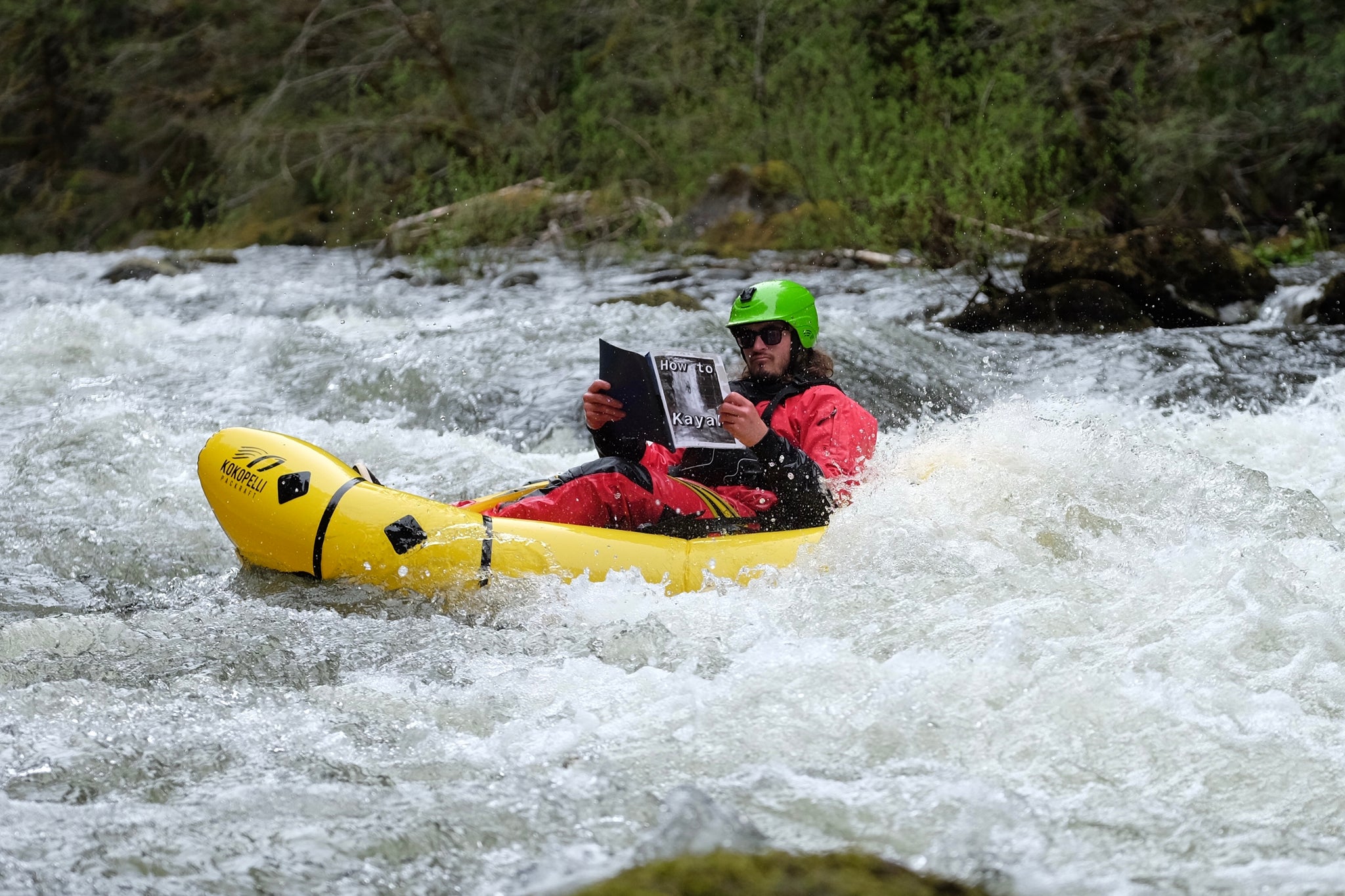 Reading How to Kayak book while packrafting a whitewater rapid