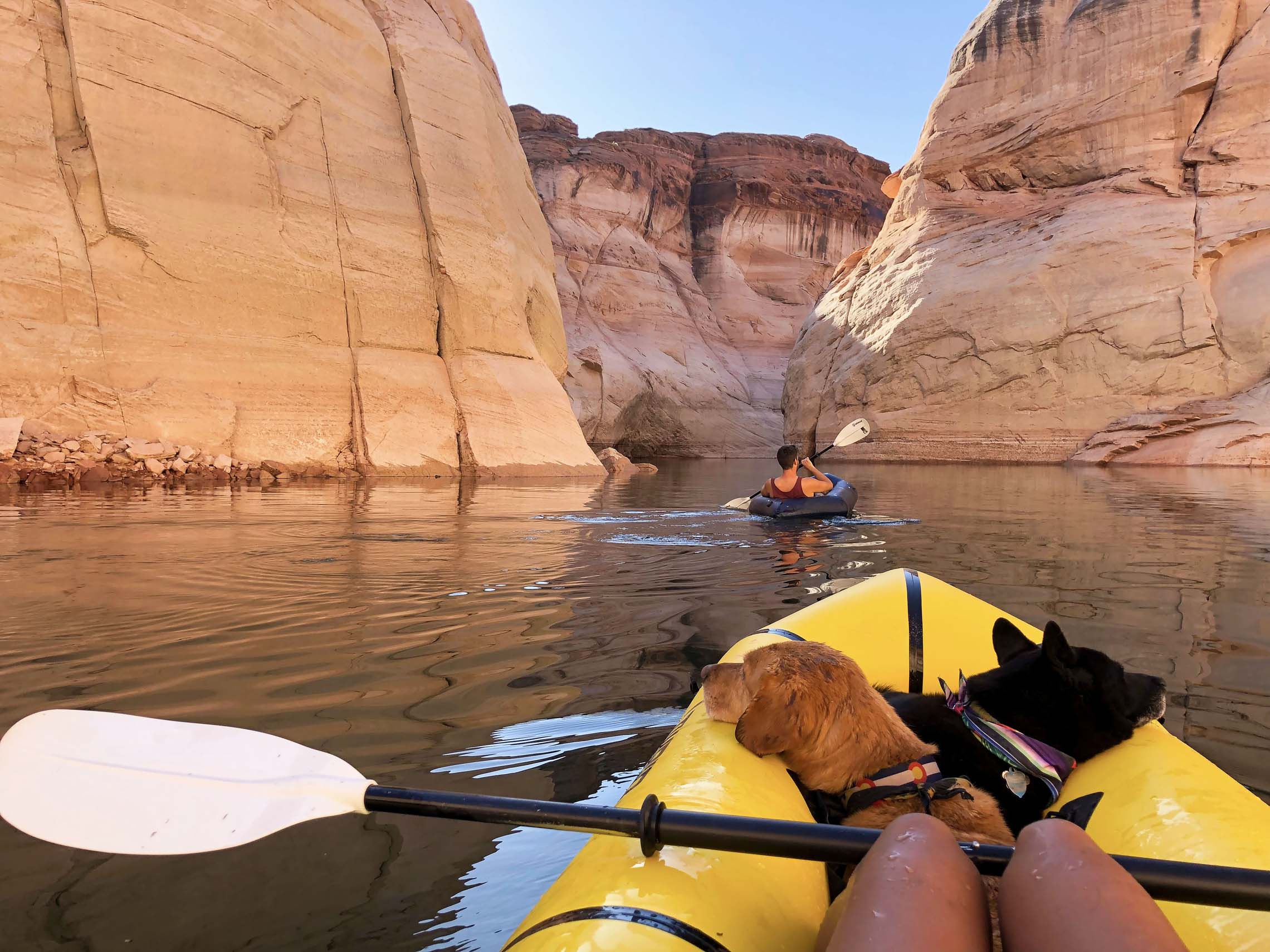 Dog and a person inside a packraft on water surrounded by boulders. Vanlife to packrafting put-ins
