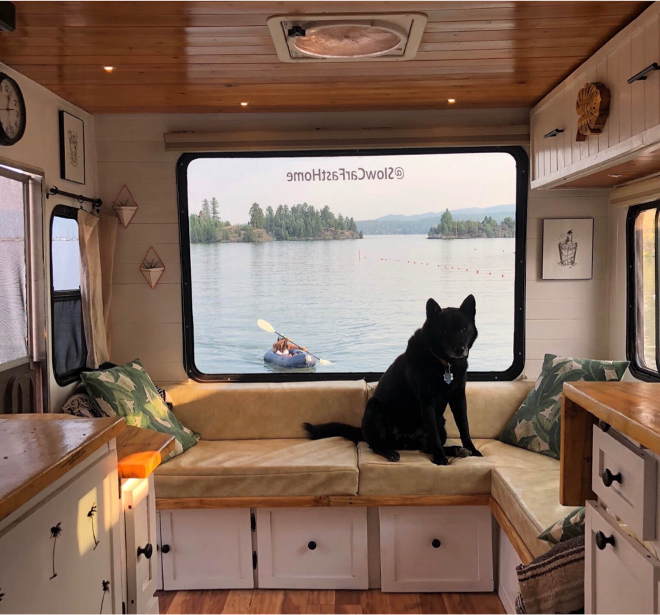 dog sitting in front of a van window looking out a packraft on a lake