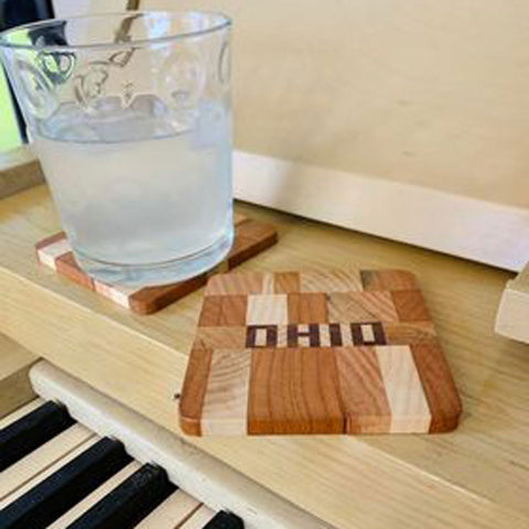 Wood Ohio coaster hand cut letters and pieces sitting on a piano 