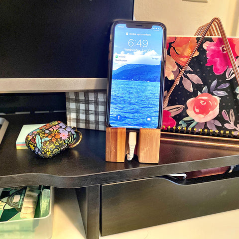 Wood phone stand with phone on a desk and desk accessories