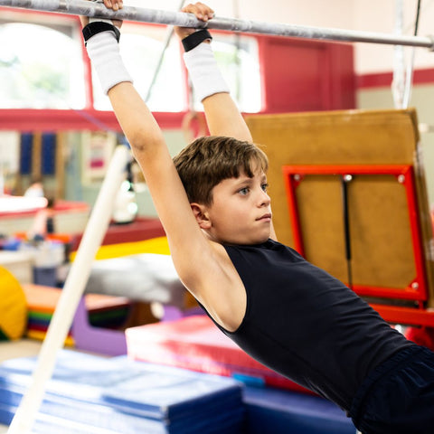 Young male gymnast on bars with Rainbow Grips Black Hook and Loop Closure on hands