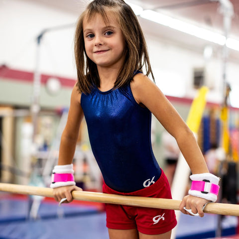 Young female gymnast with Rainbow Grips Pink Hook and Loop Closure on hands on bars