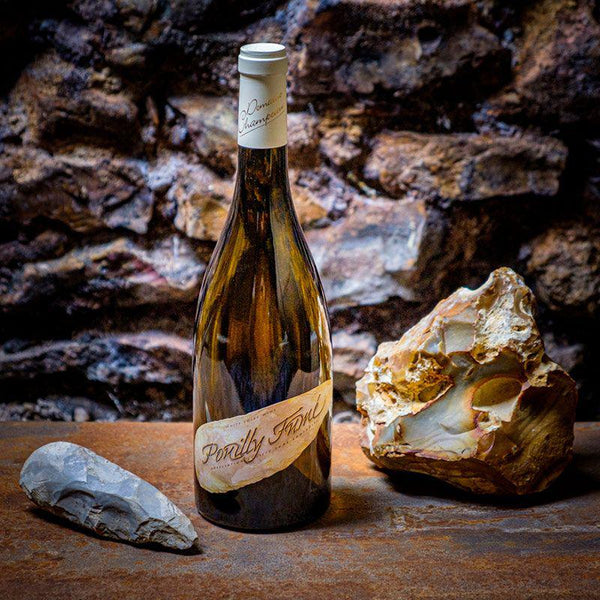 Bottle of Pouilly-Fumé wine alongside a shaped flint and a flint boulder.