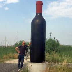Man next to tall bottle of wine sculpture