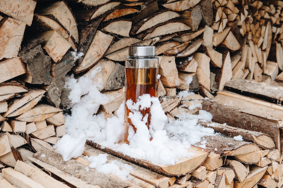 Skleněná láhev na vodu Simax ve sněhu na dřevě