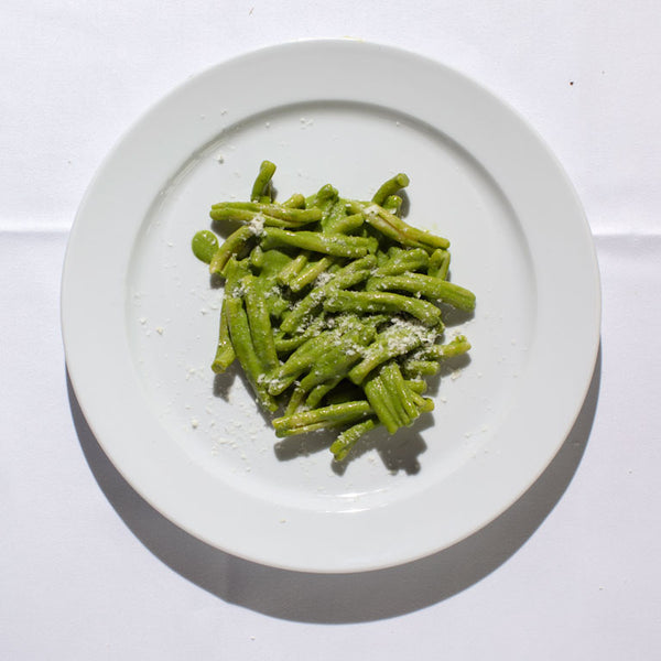 Casarecce pasta coated in bright green pesto with a sprinkling of parmesan.
