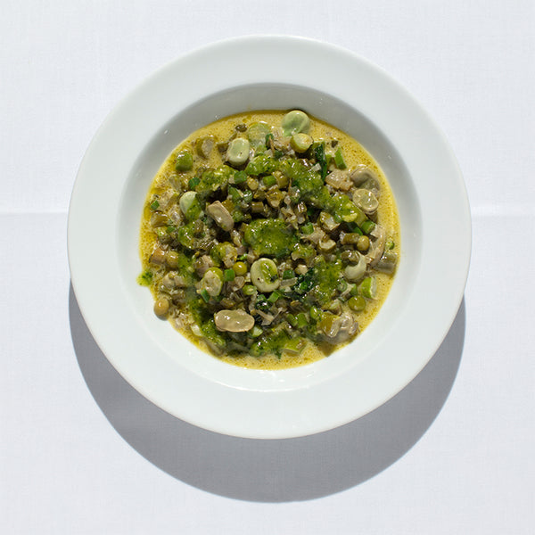 Bright green minestrone of peas, broad beans, green beans and zucchini with pesto swirled on top.