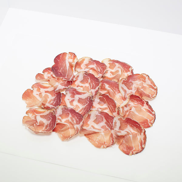 Thinly sliced Coppa di Parma on wax paper.