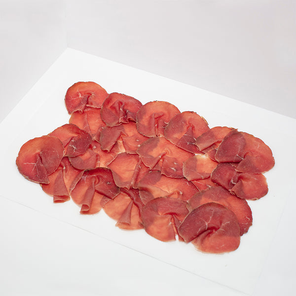 Thinly sliced Bresaola on wax paper.