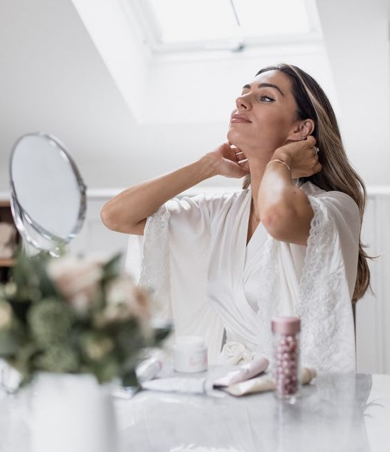 woman with multiple skincare products and a mirror