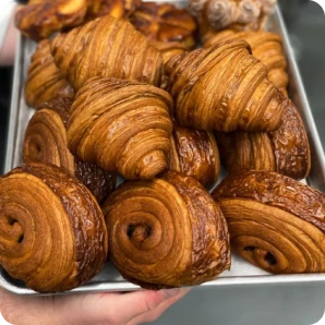 A tray of freshly baked, golden-brown croissants and pastries.