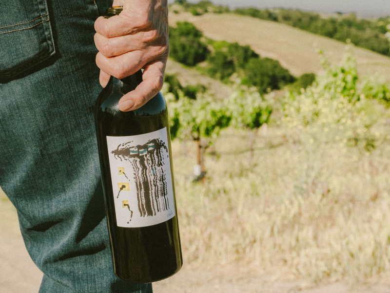 Emercy Wines winemaker holding bottle in vineyard