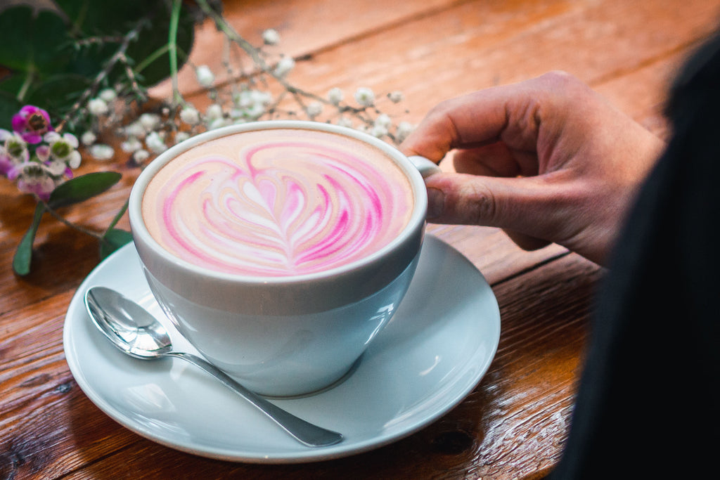 hand holding a mug full of pink coffee