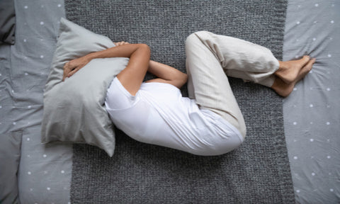 ベットに寝て頭を枕で覆う女性