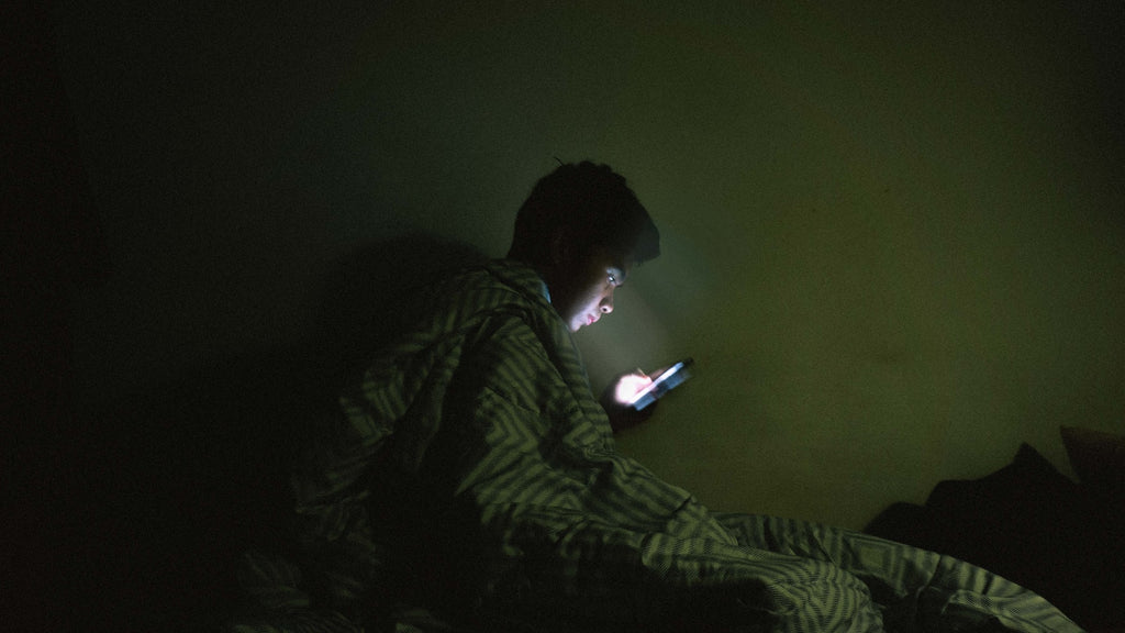 Persona que se despierta durante la noche con insomnio de mantenimiento mirando su smartphone