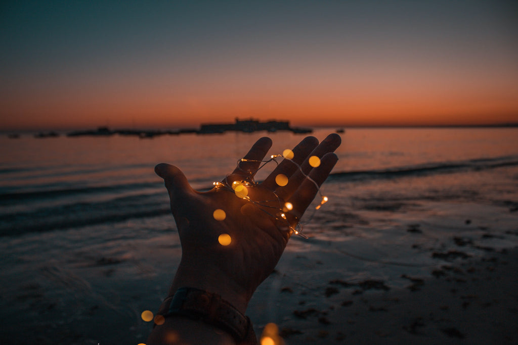 Mano iluminada frente al mar simbolizando la función regenerativa emocional del sueño