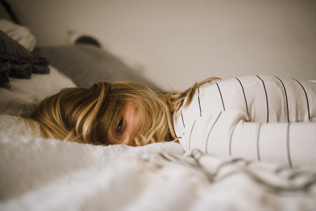 Mujer tumbada sobre una cama representando los sudores nocturnos causados por la ansiedad