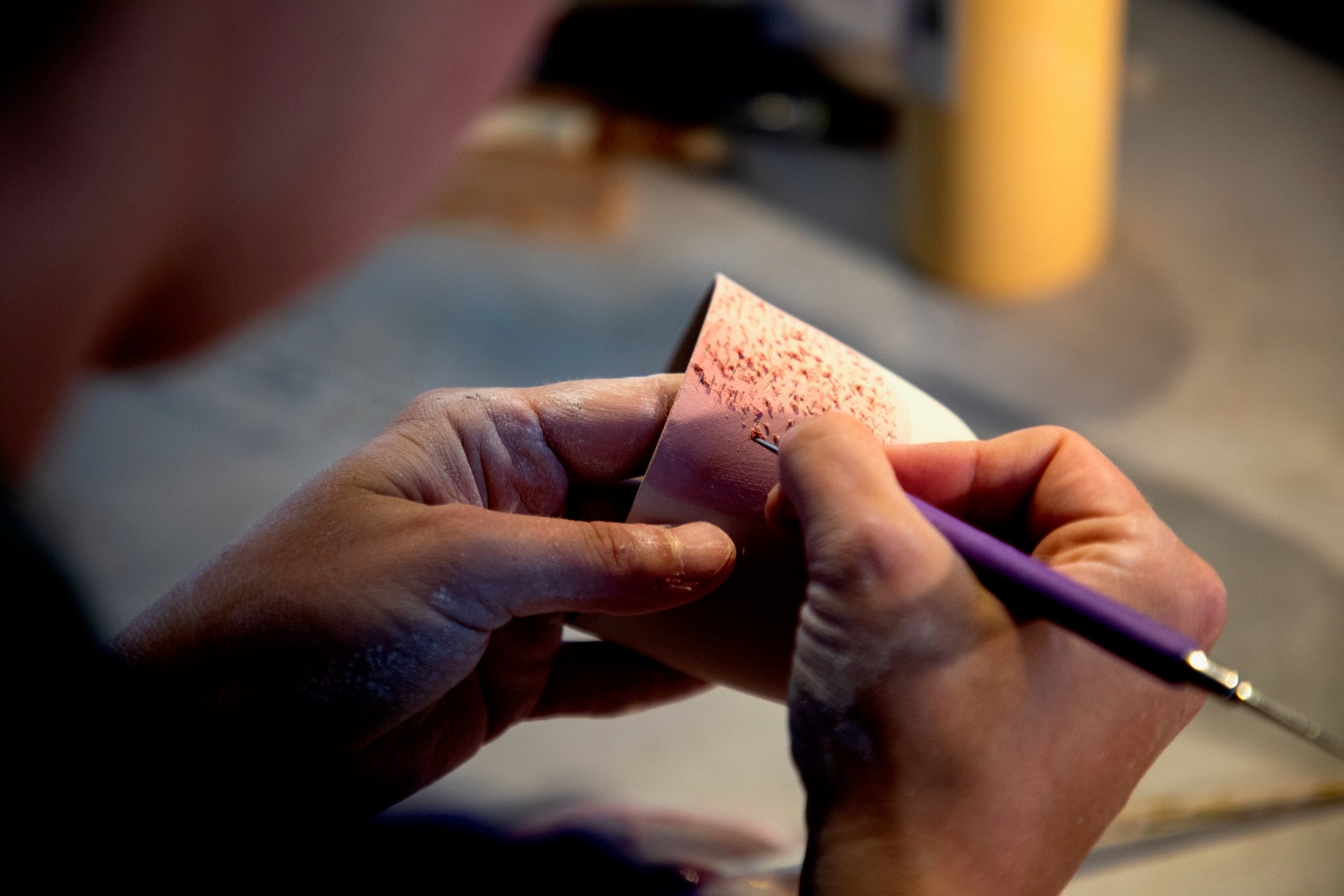 Mathilda Lovell, céramiste, décorant une pièce de céramique au pinceau