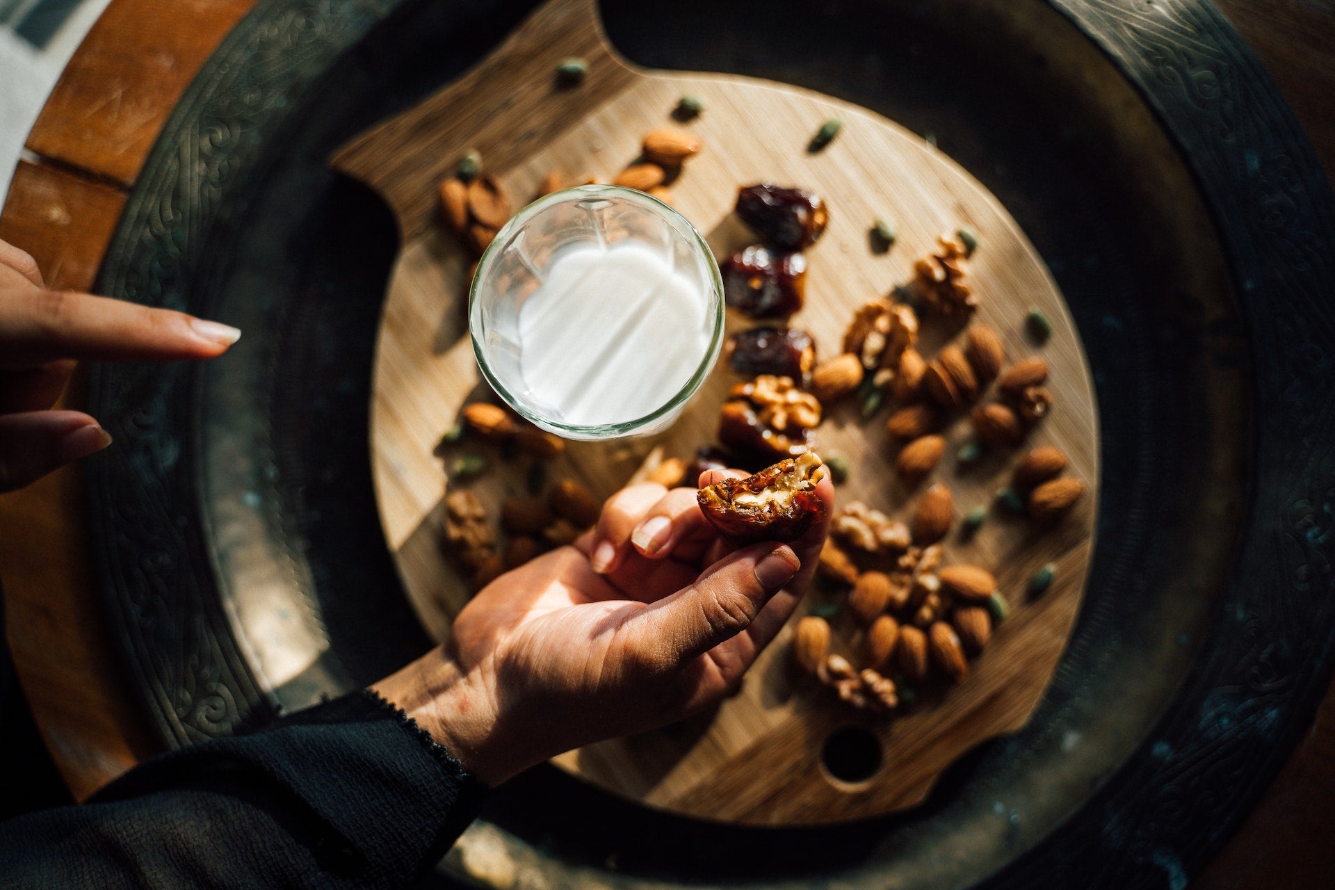 A zoomed-in image of camel milk, dates, and nuts as a woman prepares to break fast.