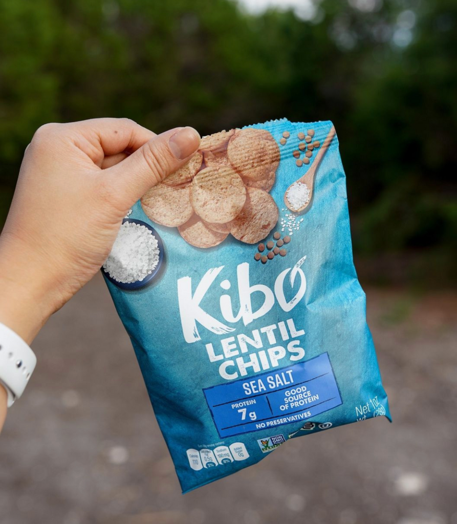 Hand holding a bag of kibo sea salt lentil chips outside
