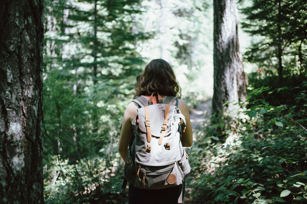 Young woman hiking with a backpack in a forest with her back turned