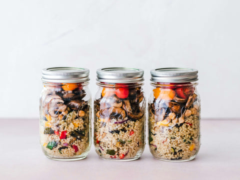 3 meal prep mason jars stand in a line filled with quinoa and veggies