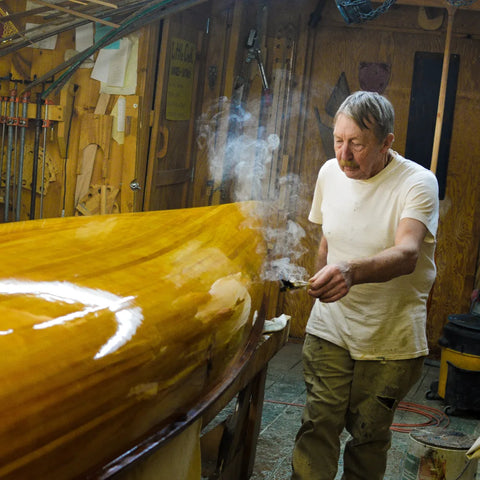 Man smudges freshly restored canoe with sage