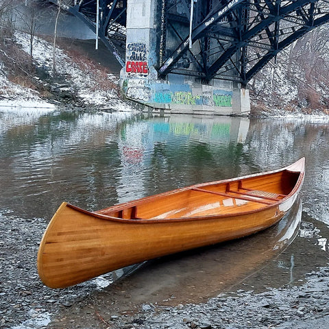 A wooden canoe on the banks of an urban river