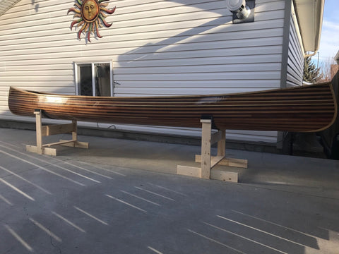 A wooden Bob's Special canoe, seen in profile outside a building from a low angle