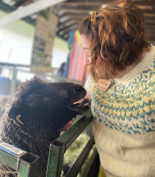 me in a cream colored. colorwork sweater patting a sheep