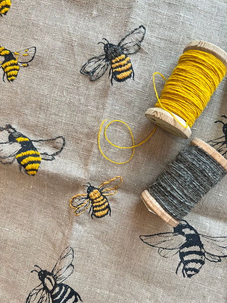 linen towel stitched with bees in yellow and gray wool