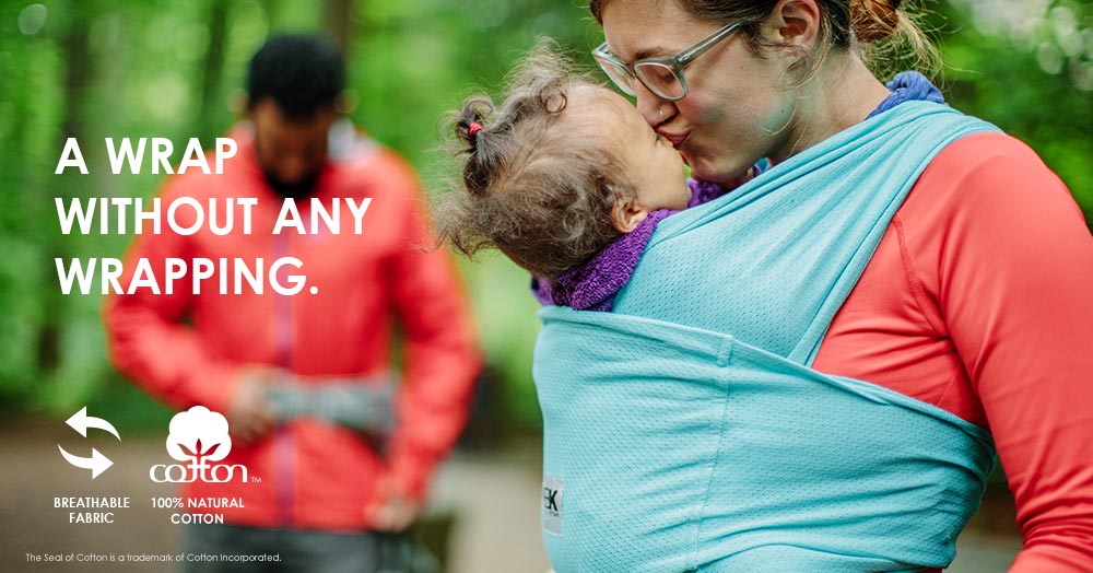 mom wearing baby in breeze carrier and kissing baby's head