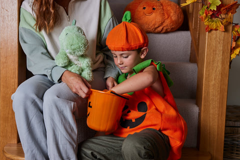 Little boy in pumpkin costume with Warmies soft toys