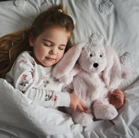 Little girl going to sleep with pink cuddly Warmies Rabbit