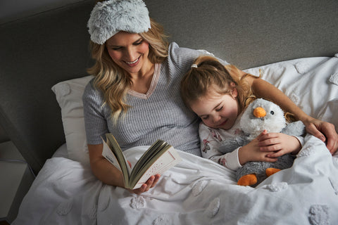 Mum and daughter in bed reading a book together