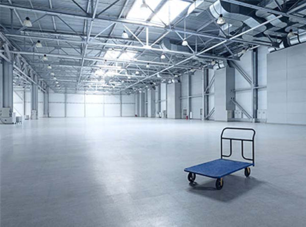 a large bright industrial space, empty with the exception of a single equipment hand cart