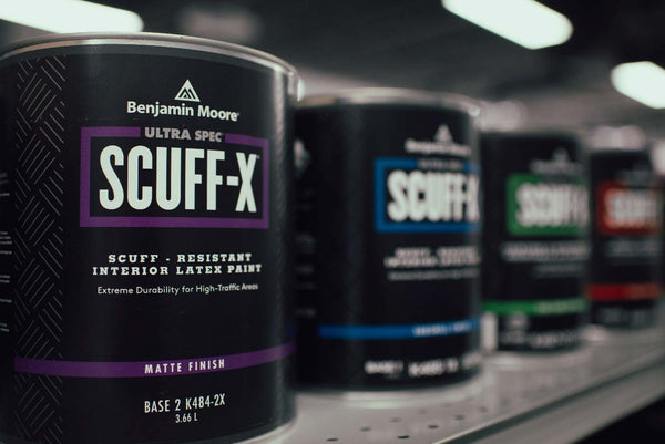 Cans of Ultra Spec Scuff-x paint on the shelves of a Benjamin Moore paint store