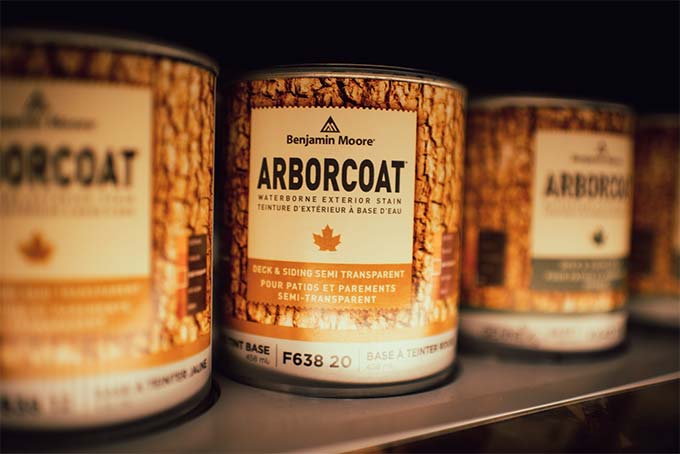 cans of Arborcoat stain by Benjamin Moore on a shelf in a paint store.