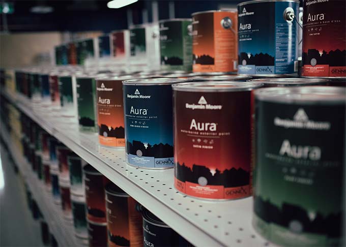 Cans of Aura paint by Benjamin Moore on a shelf in a paint store.