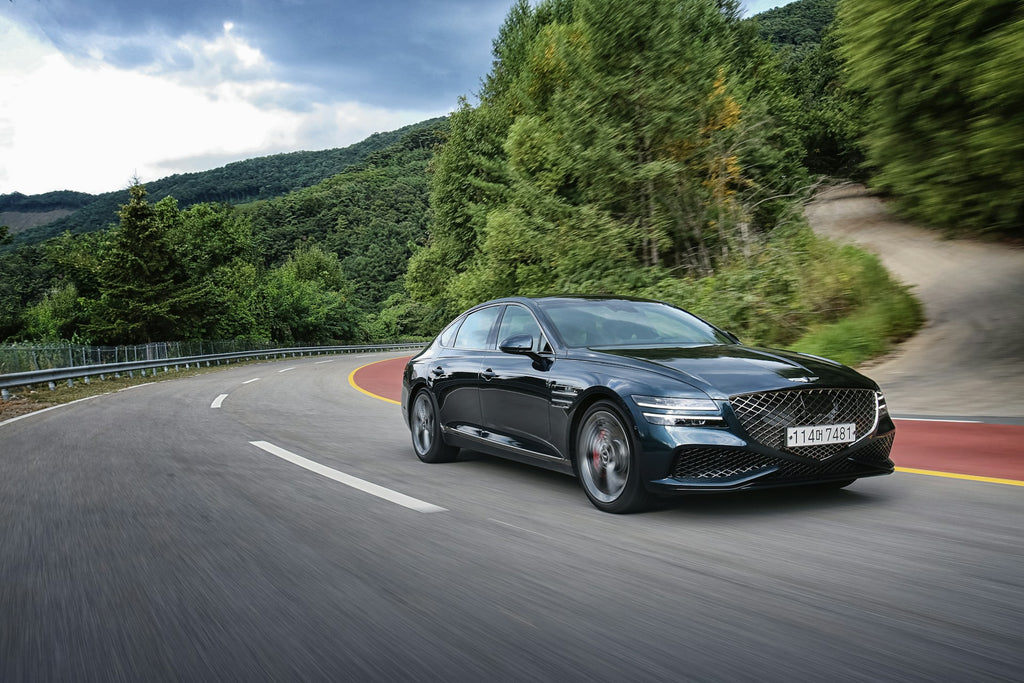 Sleek sedan cruising on a mountain road, symbolizing the secure and prepared travel ensured by having a jump box.