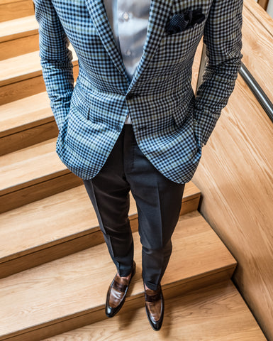 Man in a light blue sport coat, grey slacks. Standing on wooden stairs