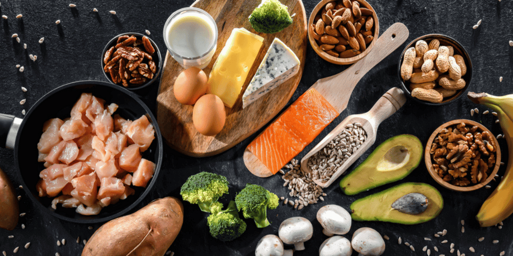 Photograph of foods that are rich in Biotin; bananas, salmon, broccoli, eggs, potatoes, chicken, pecans, cheese, milk.  Biotin is essential for healthy skin, nails and especially hair!