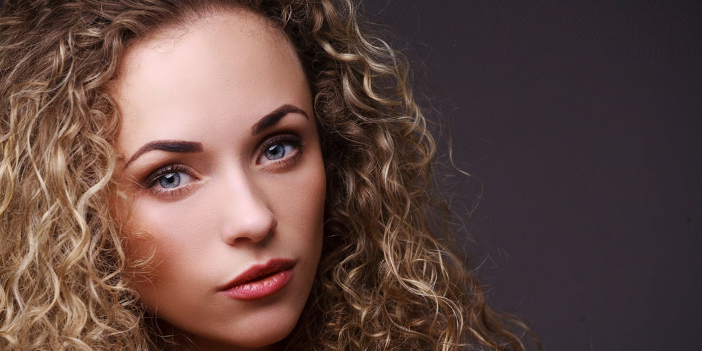 Blonde curly haired woman posing for a serious portriat with goregous volume