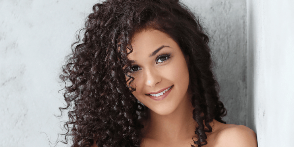 Brown curly hair woman leaning against wall