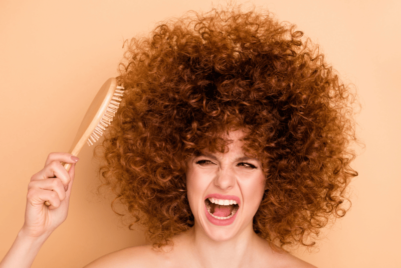 Afro Curly Hair with Frizz and untamed with a hair brush stuck in her hair