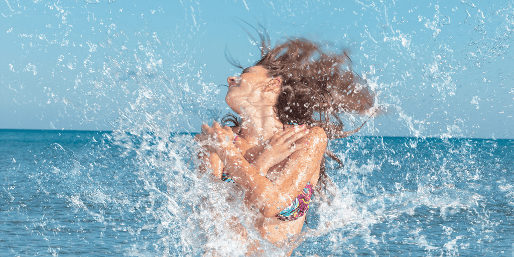 Woman Splash in ocean with beautiful hair by the Curly Life Company