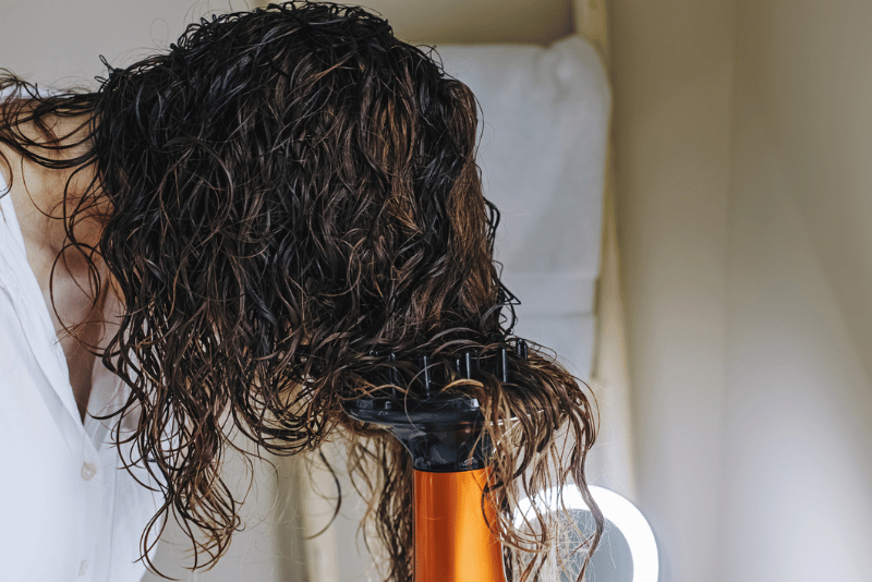 Woman using a diffuser to lock in her curls