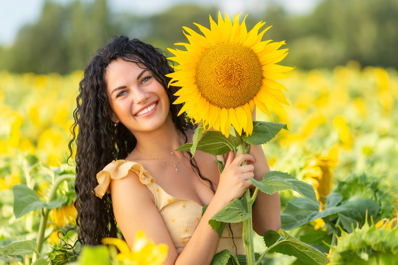 beautiful woman with brown curly hair in a field of sunflowers